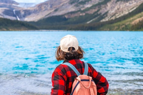 Young hiker with backpack and cap enjoying the breathtaking view of bow lake and surrounding
