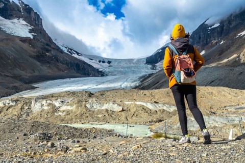 Female tourist with backpack admiring the breathtaking view of athabasca glacier in jasper national