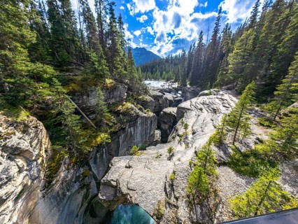 Flowing turquoise waters of mistaya canyon carve through a narrow gorge, surrounded by lush