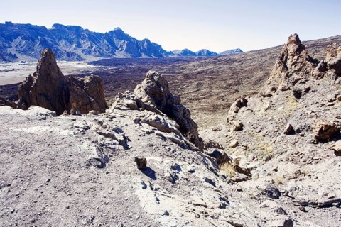 Rough volcanic landscape with rocky mountains in the background under clear sky, Pico del Teide