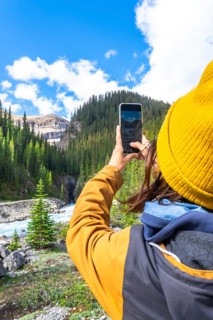 Female hiker capturing scenic waterfall photos with a smartphone along ci fuentes path on the