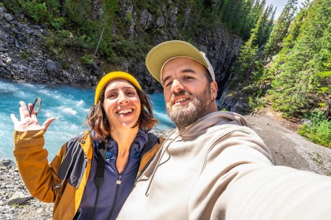 Happy couple of hikers taking a selfie at the turquoise river along the ci fuentes path waterfall