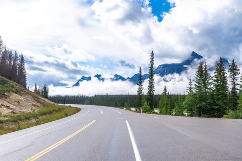 Scenic highway winds through a majestic mountain range, offering breathtaking views of the canadian