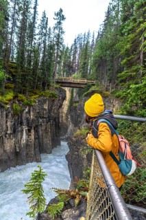Hiker observing the impressive sunwapta falls from a viewpoint in jasper national park, surrounded