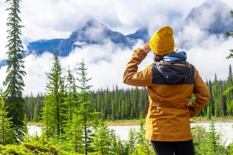 Hiker shielding her eyes while admiring the breathtaking vista of the canadian rockies along the