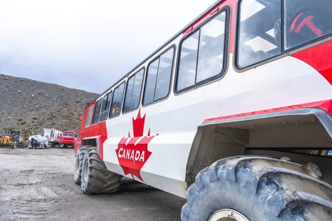 Red and white large tourist bus parked on the athabasca glacier in jasper national park, alberta,