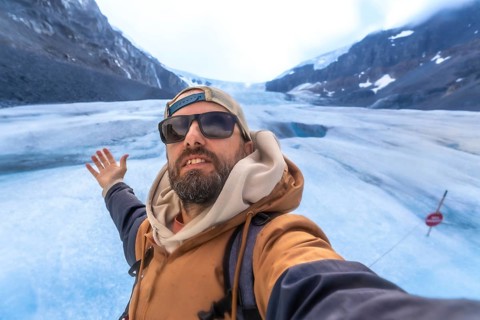 Hiker capturing a selfie with the stunning athabasca glacier in jasper national park, highlighting
