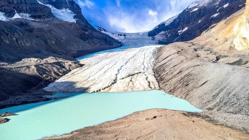 Athabasca glacier flows into a vibrant turquoise lake, showcasing the effects of climate change on