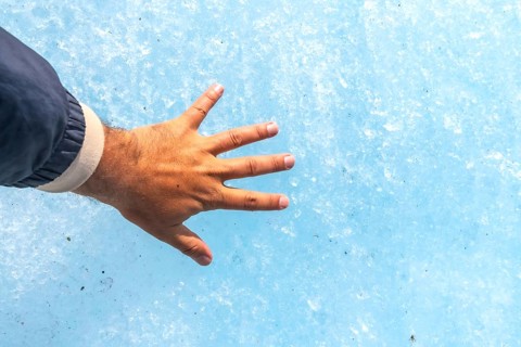 Hand of a tourist touching the millennial ice of athabasca glacier in the columbia icefield, inside