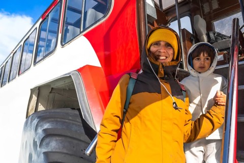Mother and son are exiting a large snowcoach after visiting the athabasca glacier in the columbia