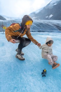 Tourist mother helping her child after slipping on the ice surface of the athabasca glacier in