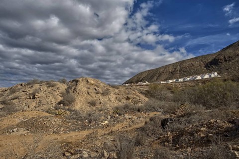 Rocky hills with cloudy sky and a settlement on the horizon, Los Cristianos Tenerife