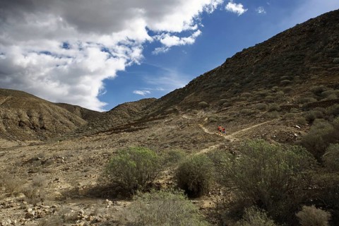 Barren mountain landscape with hikers in the distance and cloudy sky, Los Cristianos Tenerife