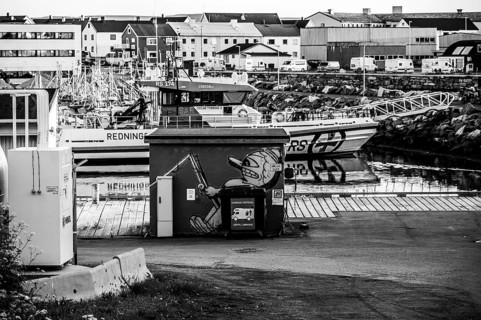 A quiet harbour with boats and graffiti on a building in black and white. Industrial atmosphere,
