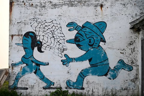 Mural in which a fisherman catches a woman with a net. By Husk Mit Navn. Vardö street art