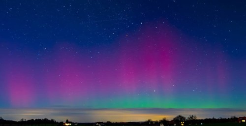 Glowing polar lights in shades of purple and green under a clear starry sky, EXPO Observatory