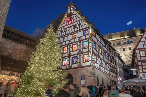 Illuminated Christmas tree with the historic Pilate House with advent calendar, in the evening