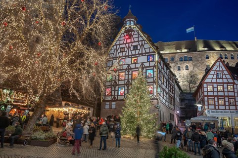 Christmassy illuminated square with the historic Pilate House with advent calendar, in the evening