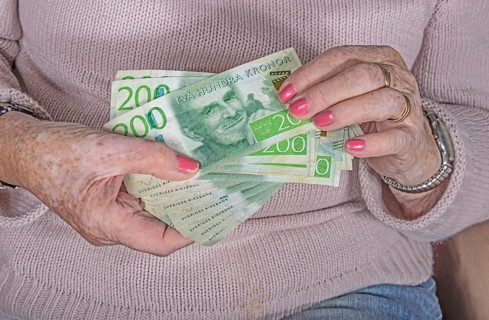 An elderly woman's hands holding Swedish 200-krona banknotes