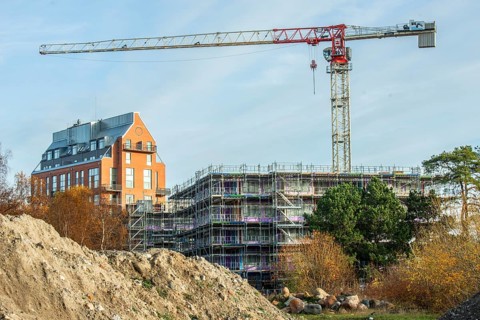 Construction site with completed high-rise building, house under construction and construction
