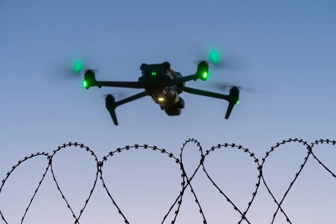Symbolic picture, drone with glowing propellers over waves of barbed wire, airport, threat,