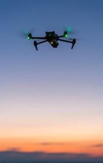 Drone floats in soft evening sky with green lights