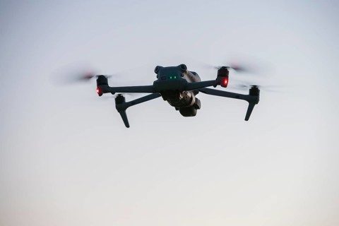 Flying drone with illuminated propellers at dusk