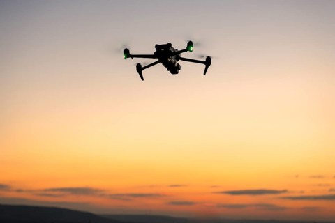 Drone in silhouette flying in front of a colorful sunset