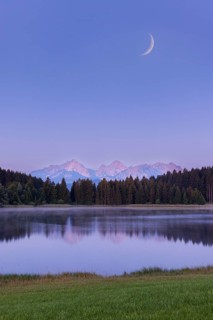 Quiet lake in front of mountains and forest with a narrow moon in the sky, Hegratsrieder See near