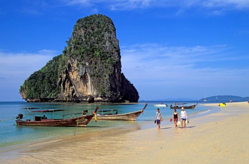 Rocks in the sea, people and longtail boats on Pranang Cave beach, two years in front of the