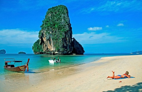 Rocks in the sea, people and longtail boat on Pranang Cave beach, two years in front of the