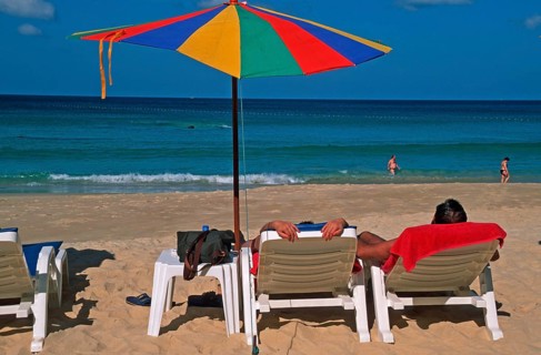 People holding umbrellas and sun loungers on Karon Beach, two years in front of the tsunami, Ko