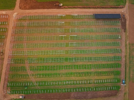 Aerial view of a solar plant on green fields with visible technical structures, energy transition,