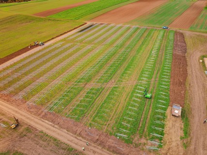 Green field with commencing construction of solar systems, tractors in use, energy transition,