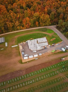Autumn aerial view of a building materials warehouse with surrounding fields and an adjacent road,
