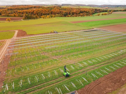 Wide fields with solar panels and green landscape in the background, energy revolution,