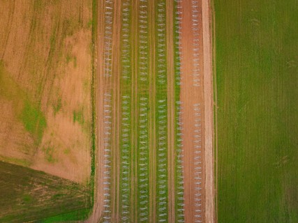 Aerial view showing fields in regular patterns with solar racks and arable land, energy transition,