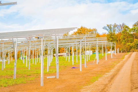 Extensive site with metal structures for solar panels and autumn sky, energy revolution,