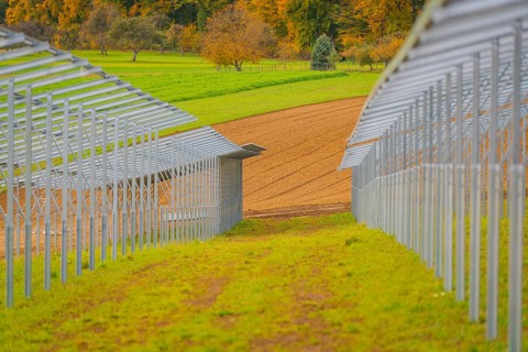 Metal frame for solar panels in autumn landscape with green meadows, energy revolution,