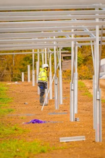Craftsman in safety clothing working on the construction of solar panels in an open field,