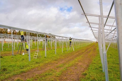 Workers assemble metal structures on a construction site in a grassy field, Energiewende,
