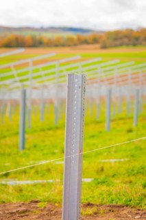 Close-up of a metal rod that is part of a larger field installation, with blurred landscape in the