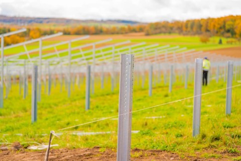 Metal poles along a field under cloudy sky with autumn landscape in the background, Energiewende,