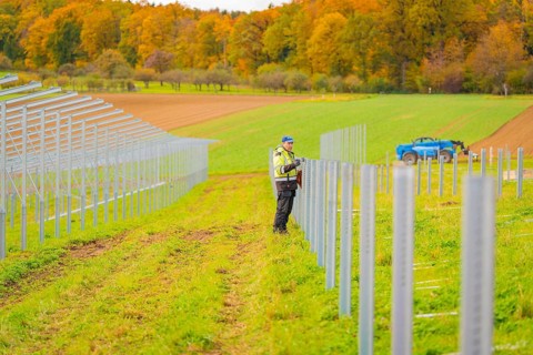 A worker installs poles in a field on a clear autumn day, Energiewende, construction of PV open