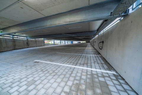 Empty covered parking lot with concrete structure and marked parking spaces, parking garage