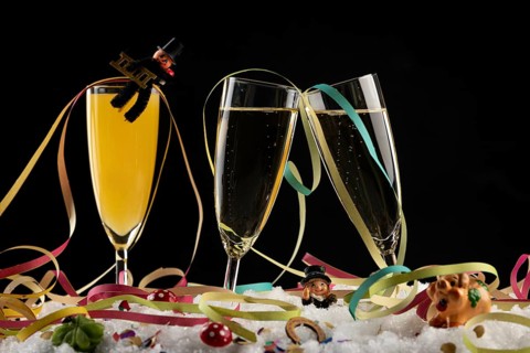 Three champagne glasses with lucky charms for the New Year and streamers in the snow