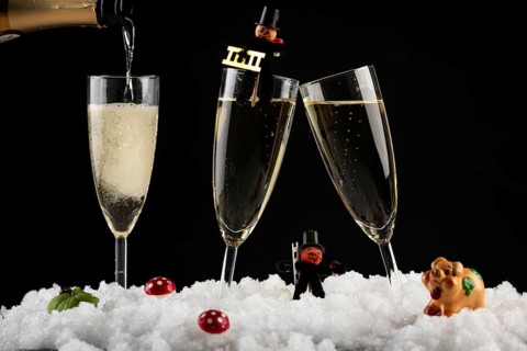 Three champagne glasses with lucky charms for New Year in the snow