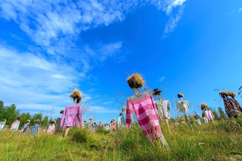 Artwork outdoor installation The silent people of Reijo Kela Straw dolls wear colorful clothes in a