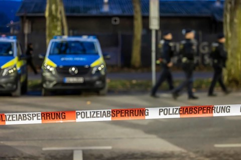 Flutter tape with the inscription police barrier. Behind them, police vehicles. Stuttgart,