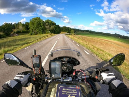 Motorcycle ride on a deserted road through a green landscape under blue sky with clouds